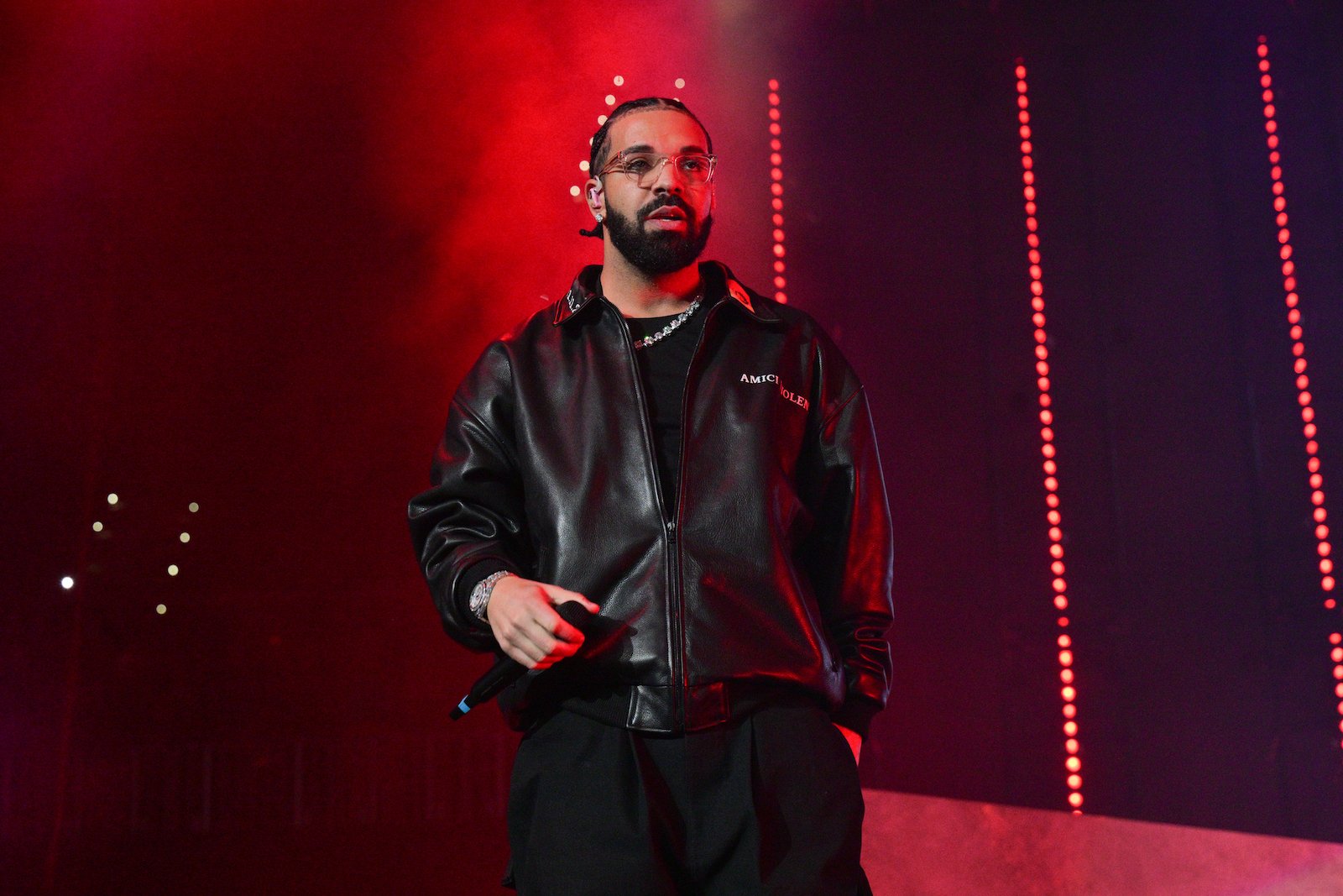 Drake, who was performing at the Apollo theater when a fan fell from the balcony, on stage wearing a black leather jacket