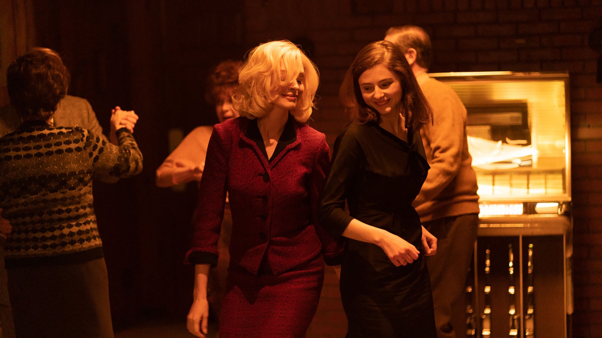 'Eileen' Anne Hathaway as Rebecca and Thomasin McKenzie as Eileen dancing next to each other, smiling.
