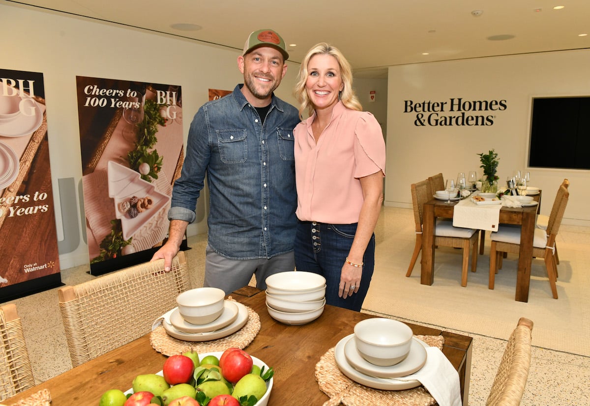 "Fixer to Fabulous" stars Dave and Jenny Marrs smile and pose together at a table laid with dishes.