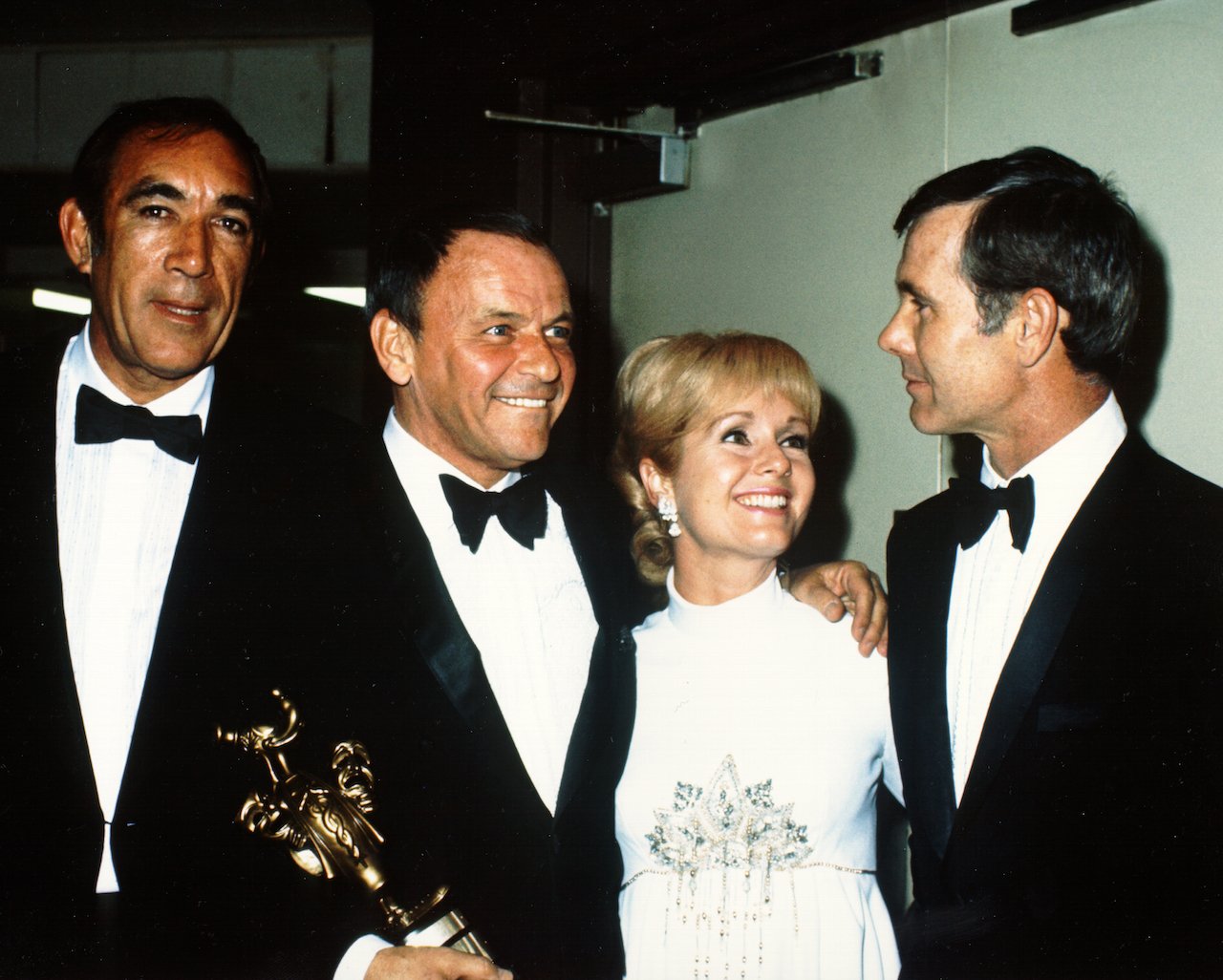 Anthony Quinn, Frank Sinatra, Debbie Reynolds, and Johnny Carson chat backstage as Sinatra holds an award he won circa 1973.