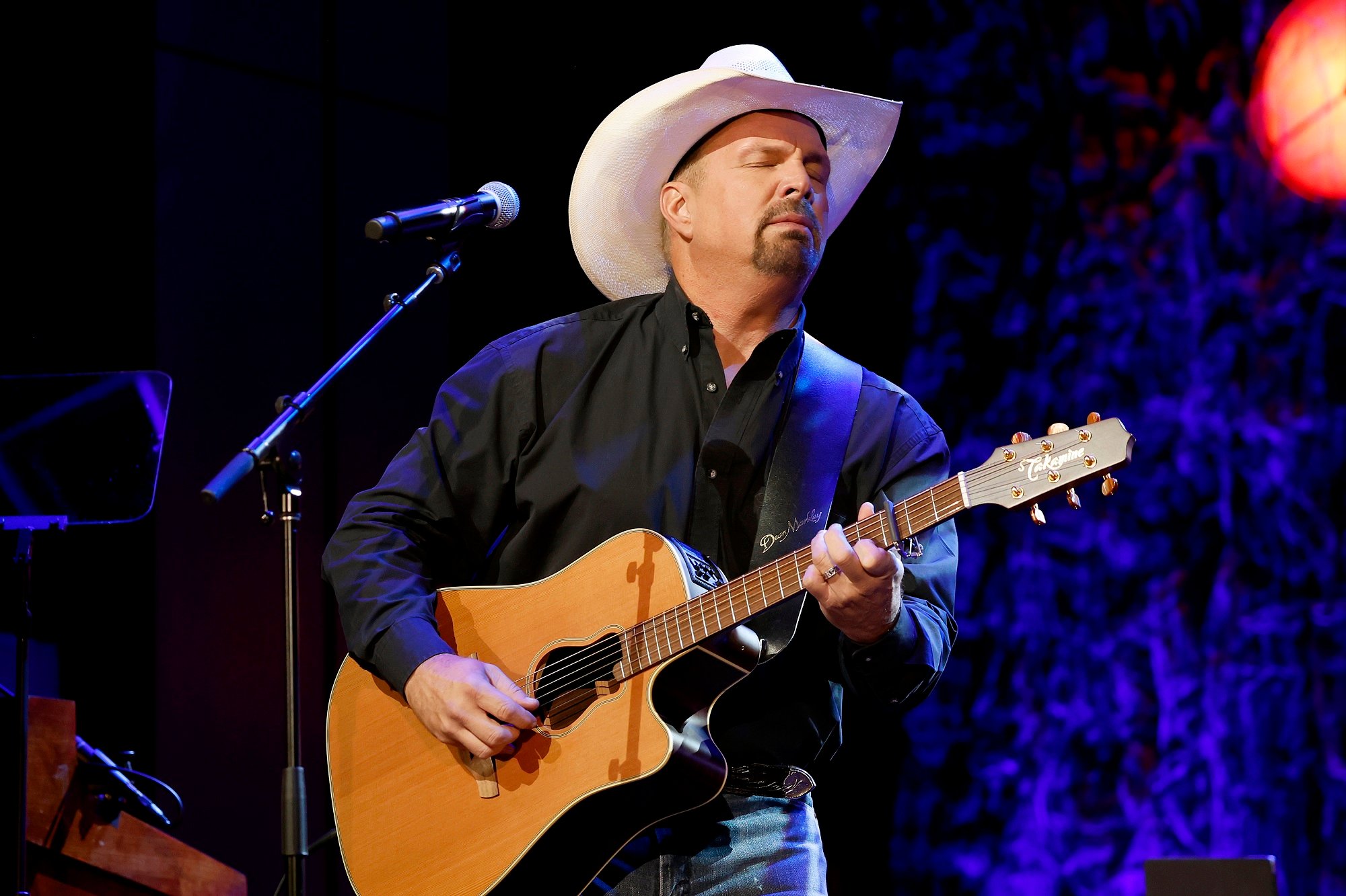 Garth Brooks plays an acoustic guitar on stage