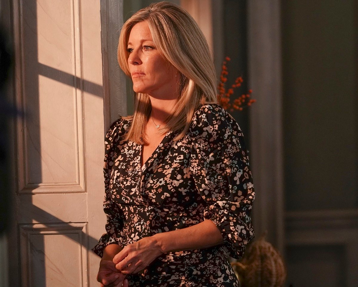 'General Hospital' star Laura Wright wearing a black floral dress and staring out a window on set of the soap opera.