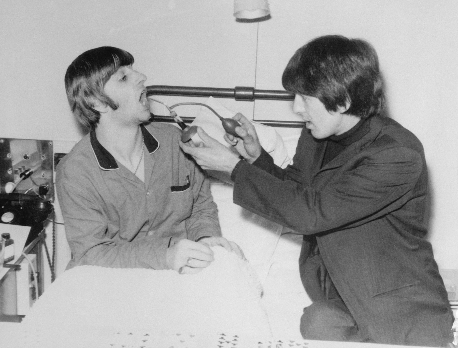 Beatle drummer Ringo Starr as fellow-Beatle George Harrison sprays his throat at University College Hospital