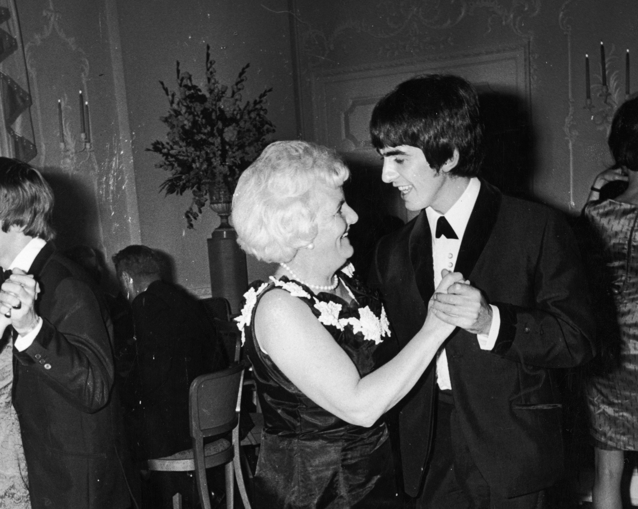 A black and white picture of George Harrison dancing with his mom, Louise.