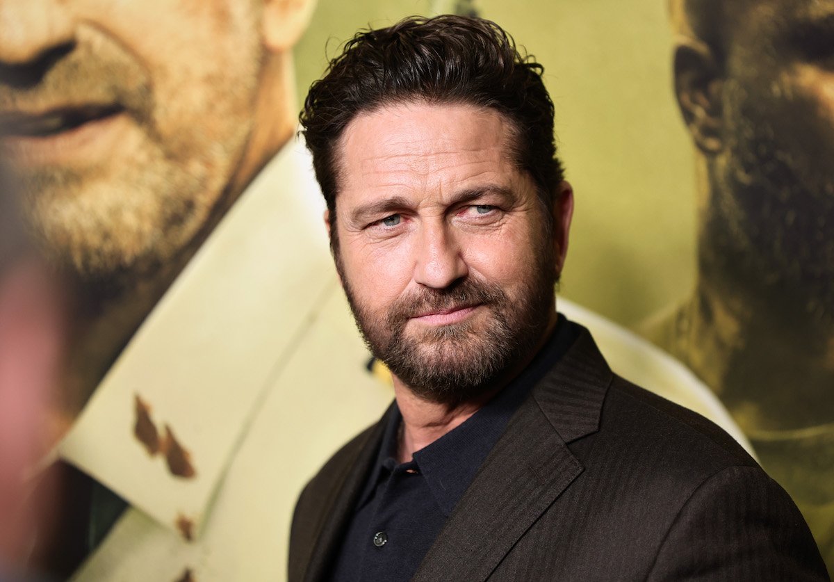 Gerard Butler poses in front of the "Plane" movie poster.