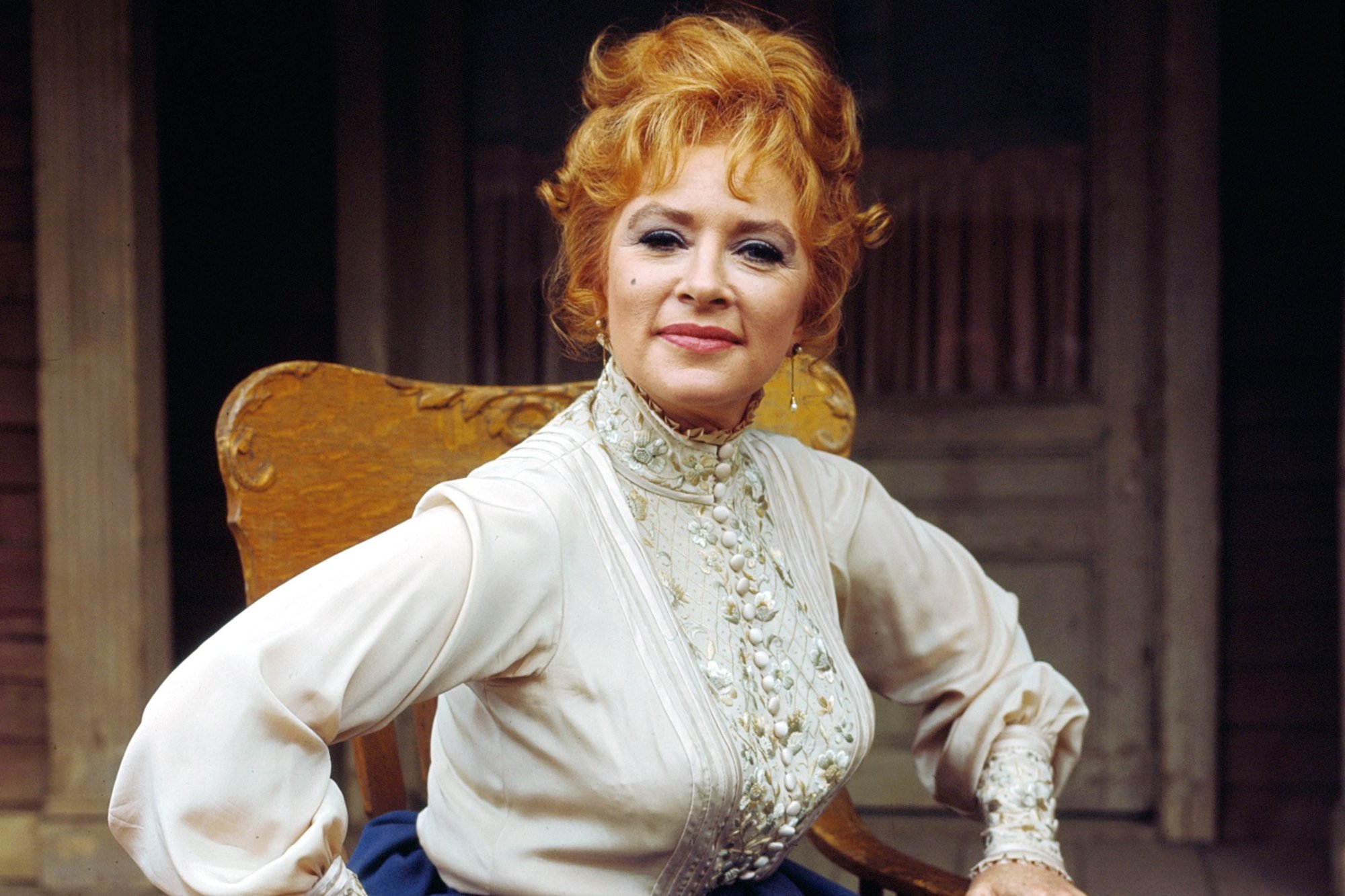 'Gunsmoke' Amanda Blake as Miss Kitty Russell sitting in a wooden chair with her hands on the arms of the chair