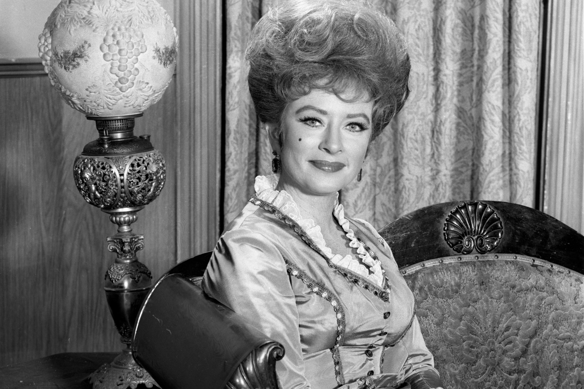 'Gunsmoke' Amanda Blake as Miss Kitty Russell in a black-and-white picture sitting on a couch