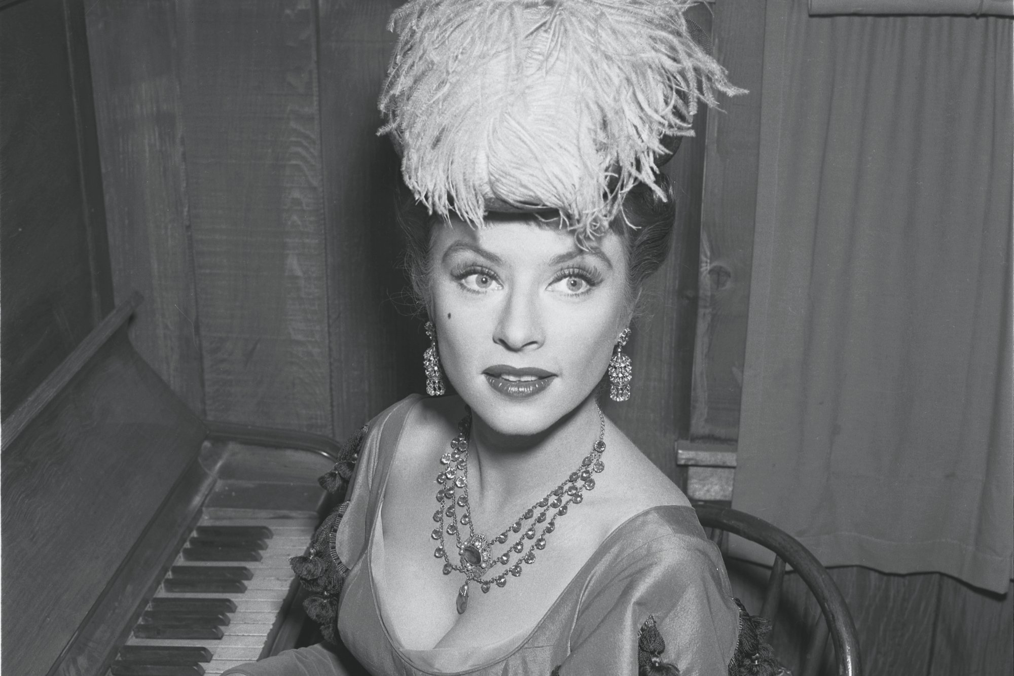 'Gunsmoke' Amanda Blake as Miss Kitty Russell in her Western costume sitting at the piano with her fingers on the keys