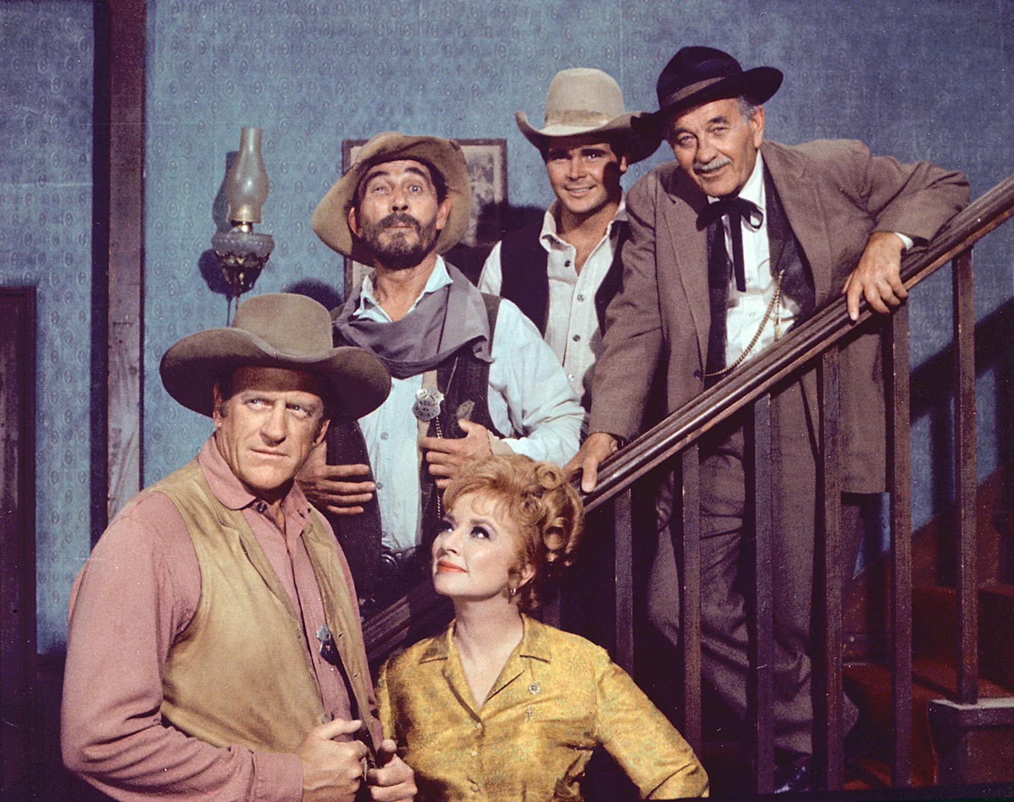 'Gunsmoke' James Arness as Matt Dillon, Amanda Blake as Miss Kitty Russell, Ken Curtis as Festus Haggen, Buck Taylor as Newly O'Brien, and Milburn Stone as Doc Adams standing along the Long Branch saloon staircase