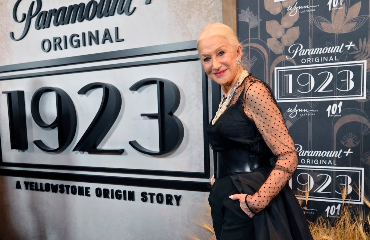 Helen Mirren poses in front of the "1923" logo at an event.