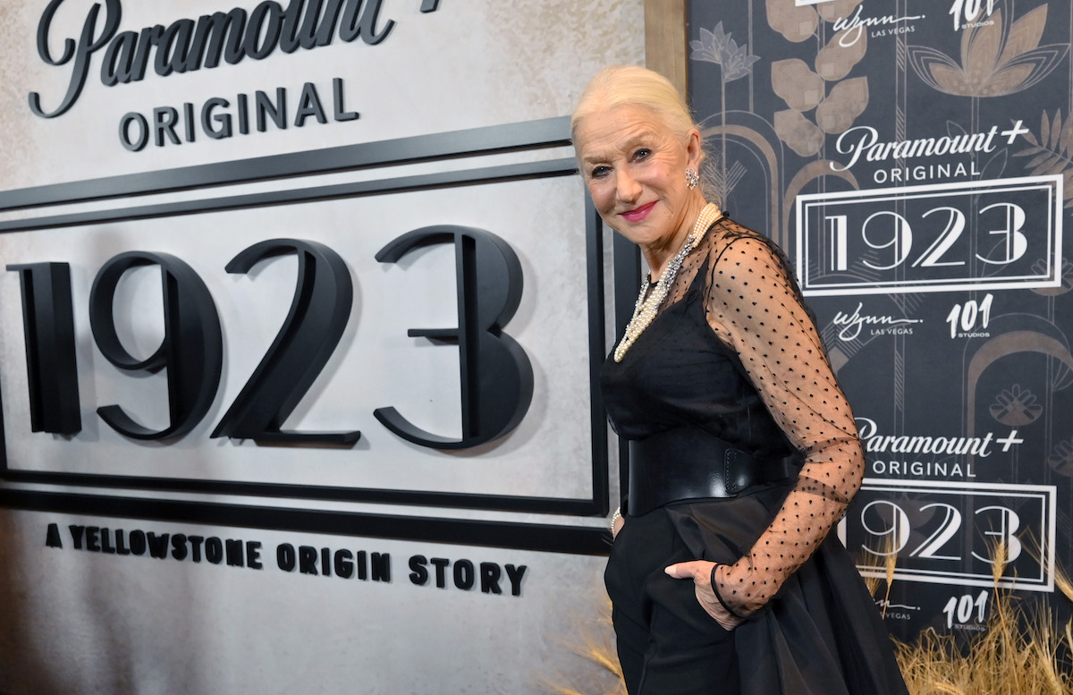Helen Mirren poses in front of the "1923" logo at an event.