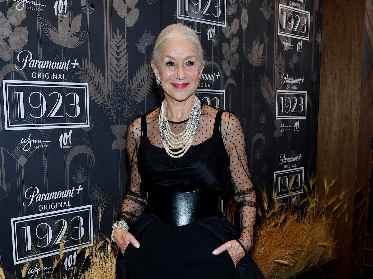 Helen Mirren poses in front of a black backdrop featuring the "1923" logo