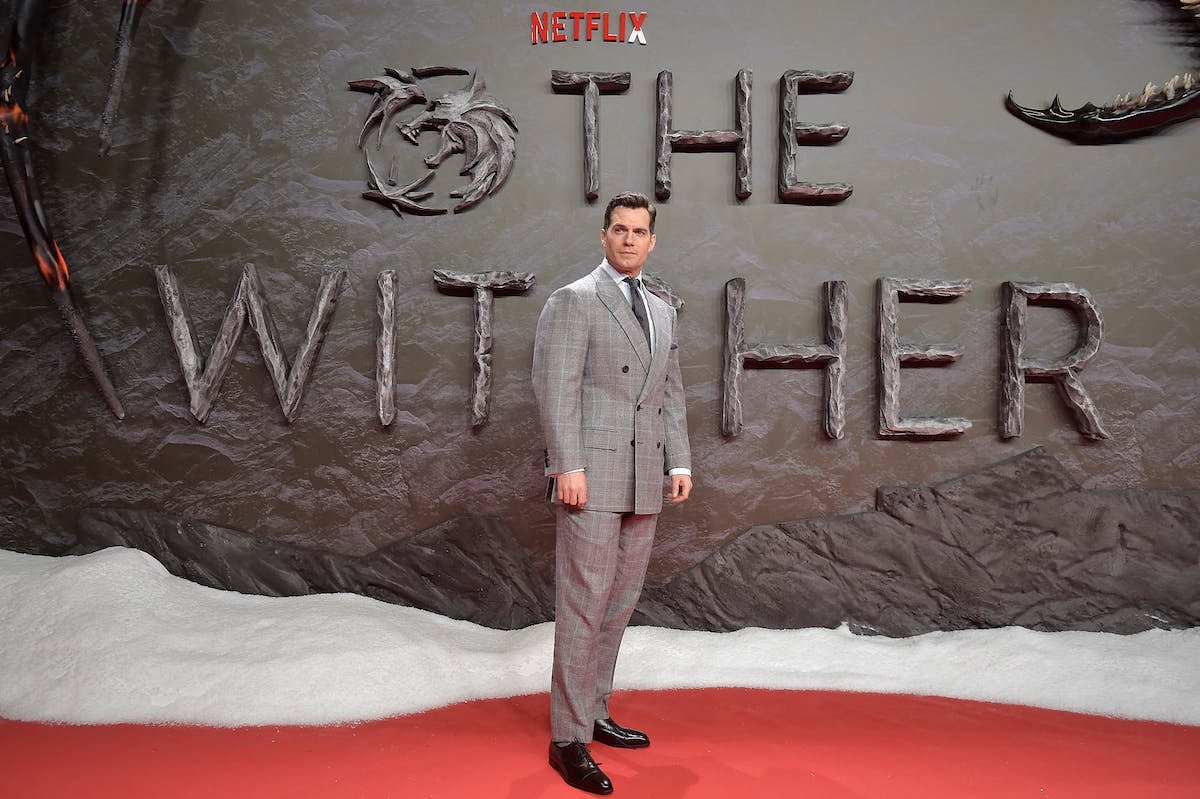 Henry Cavill poses in front of "The Witcher" logo at a premiere event.