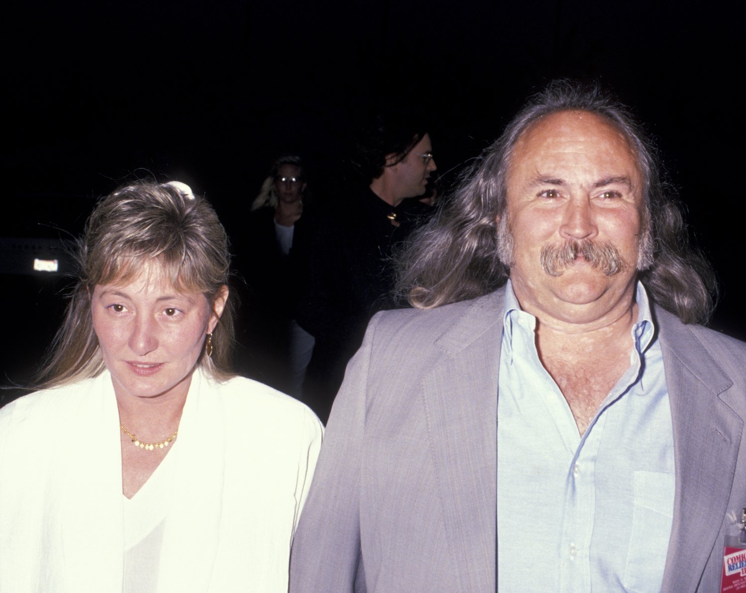 David Crosby and wife Jan Dance walking together against a black background