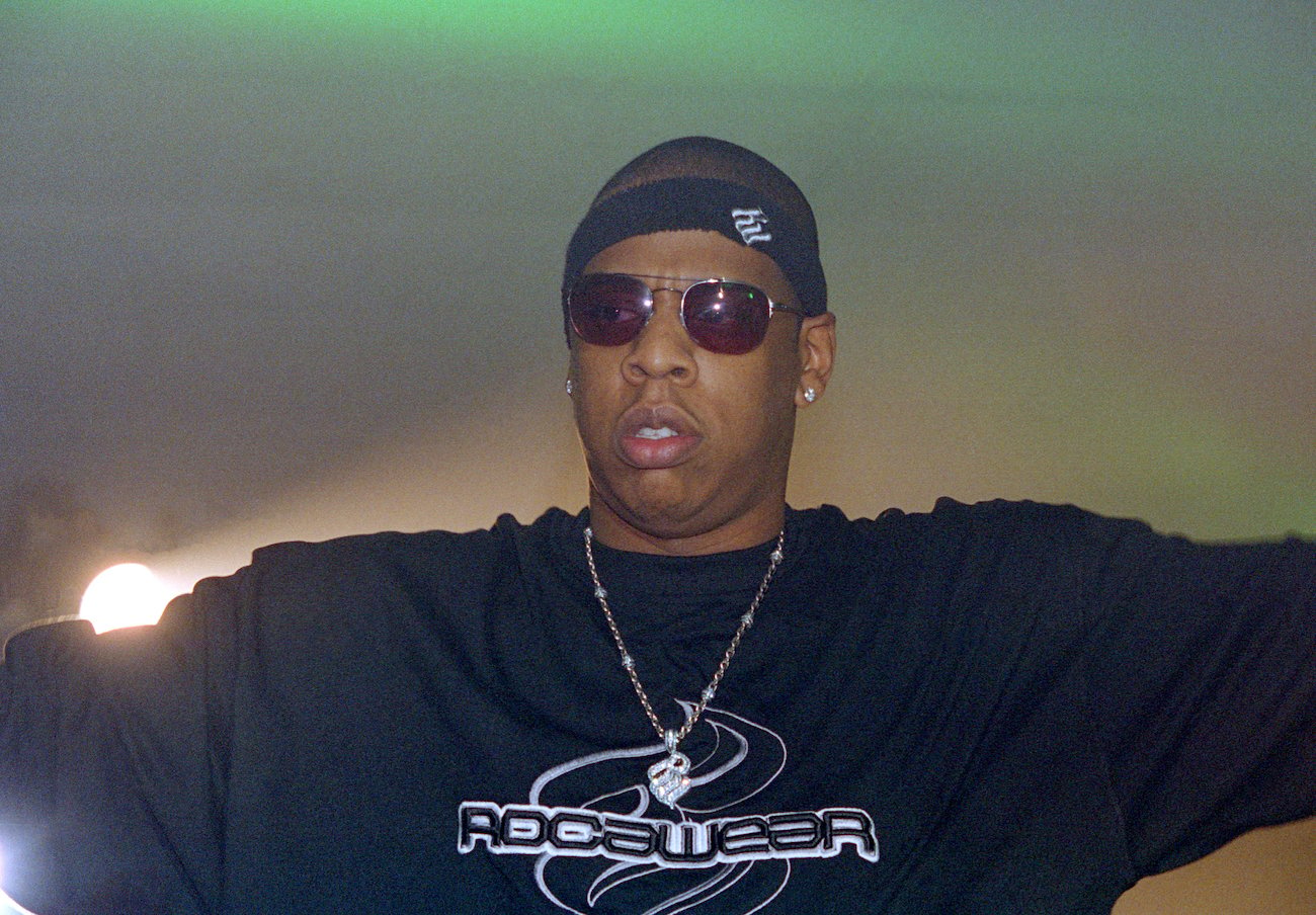 Jay-Z, rapped behind Big Pimpin with Pimp C, wearing a black T-shirt against a green backdrop
