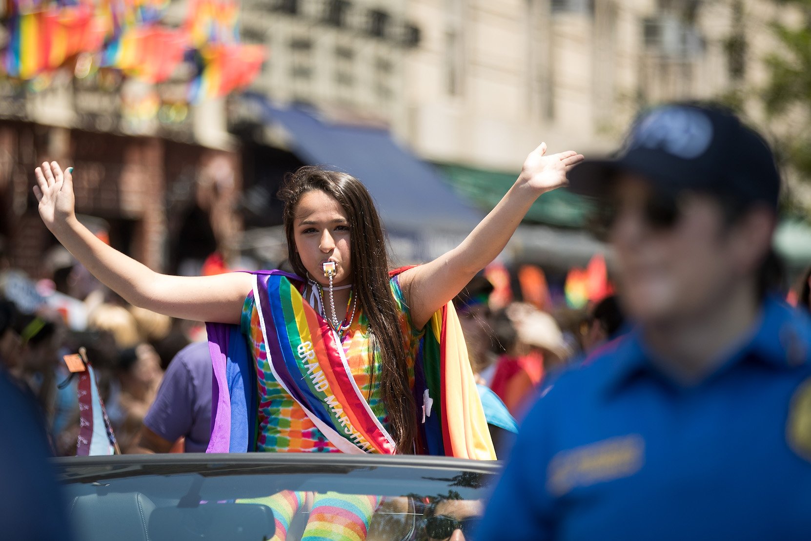 Jazz Jennings from 'I Am Jazz' Season 8 in a rainbow outfit riding in a the back of a convertible through a parade