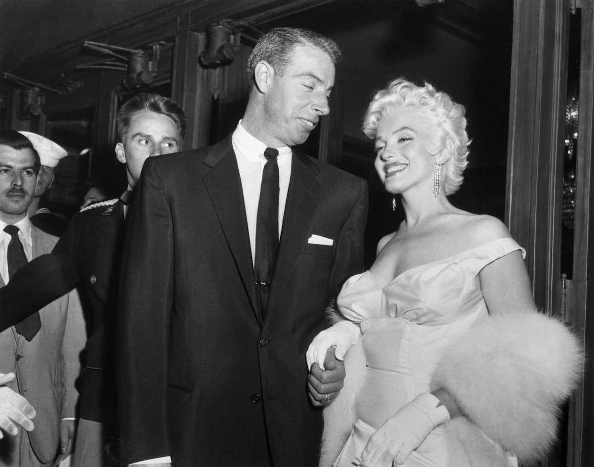 Marilyn Monroe and Joe DiMaggio attend a movie premiere in a black and white photo
