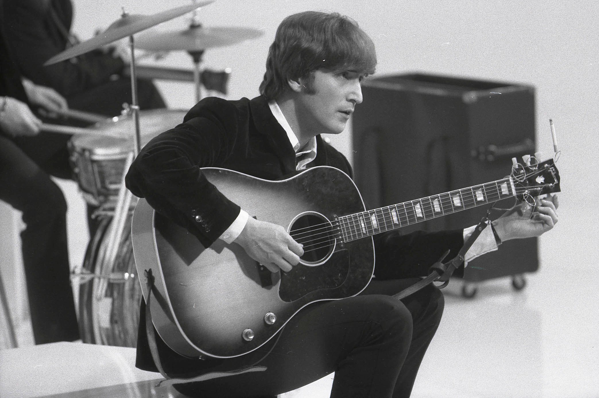 John Lennon of The Beatles tuning his guitar while filming 'A Hard Day's Night'