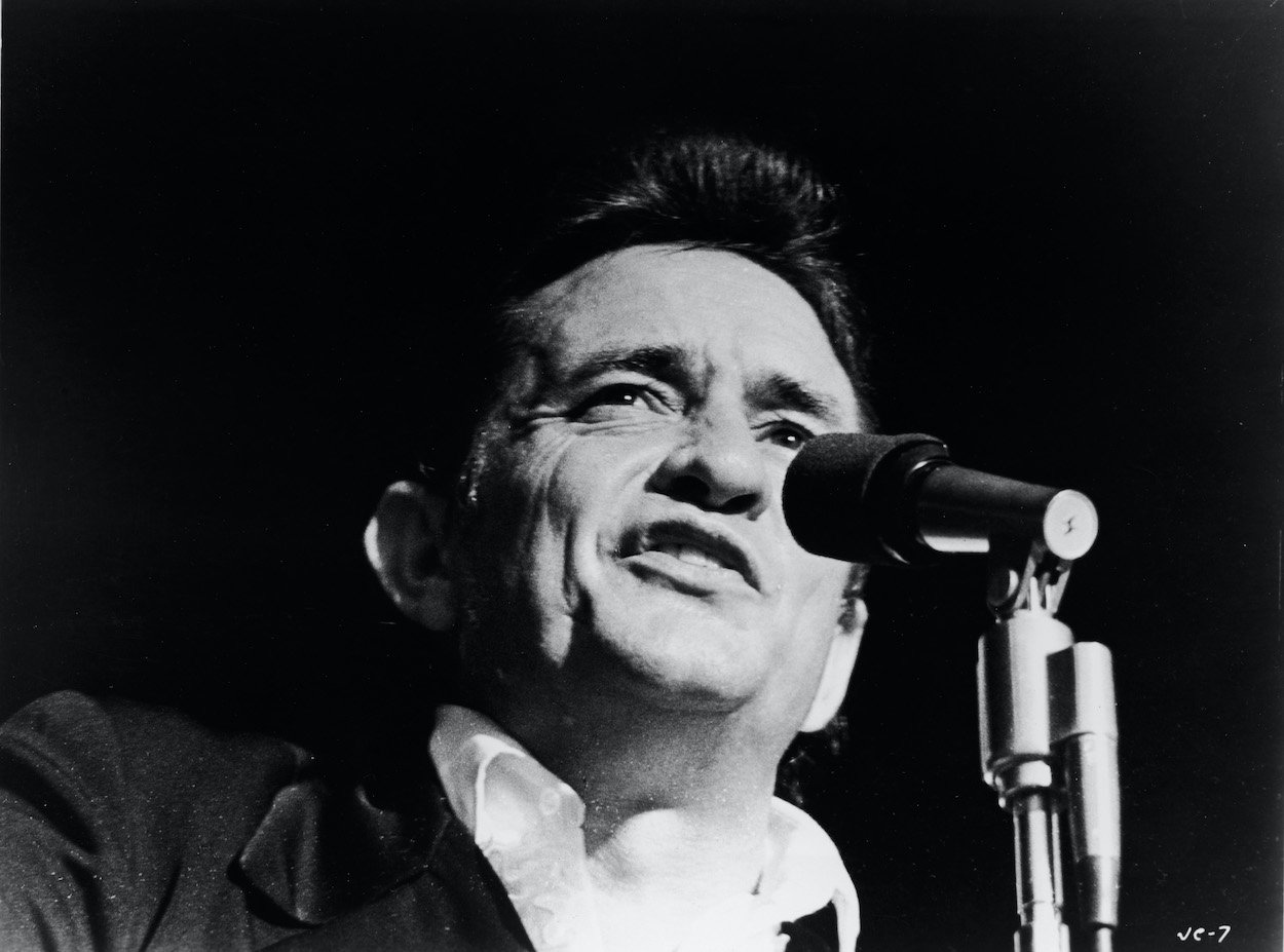 Johnny Cash singing into a microphone in a still shot taken from the 1969 movie 'Johnny Cash - The Man, His World, His Music.'