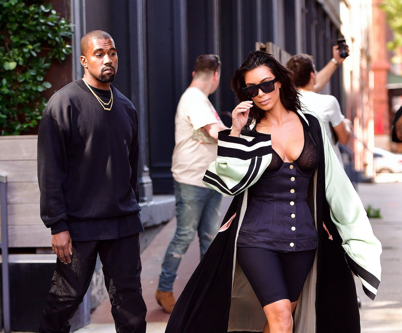 Kanye West and Kim Kardashian walk down the street in New York while fans take photos