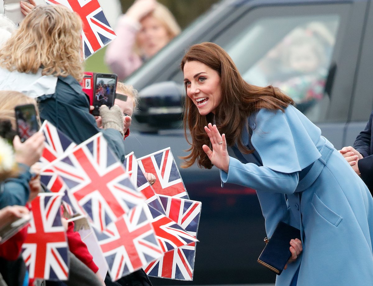 Kate Middleton, who handles attention like Prince Philip and Queen Elizabeth, according to an author, greets crowds wearing a blue coat