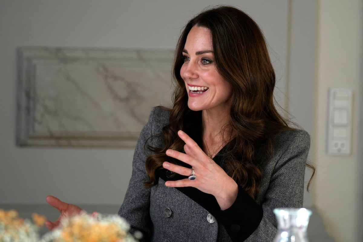 Kate Middleton, who a commentator says handles cameras like Prince Philip and Queen Elizabeth, looks on