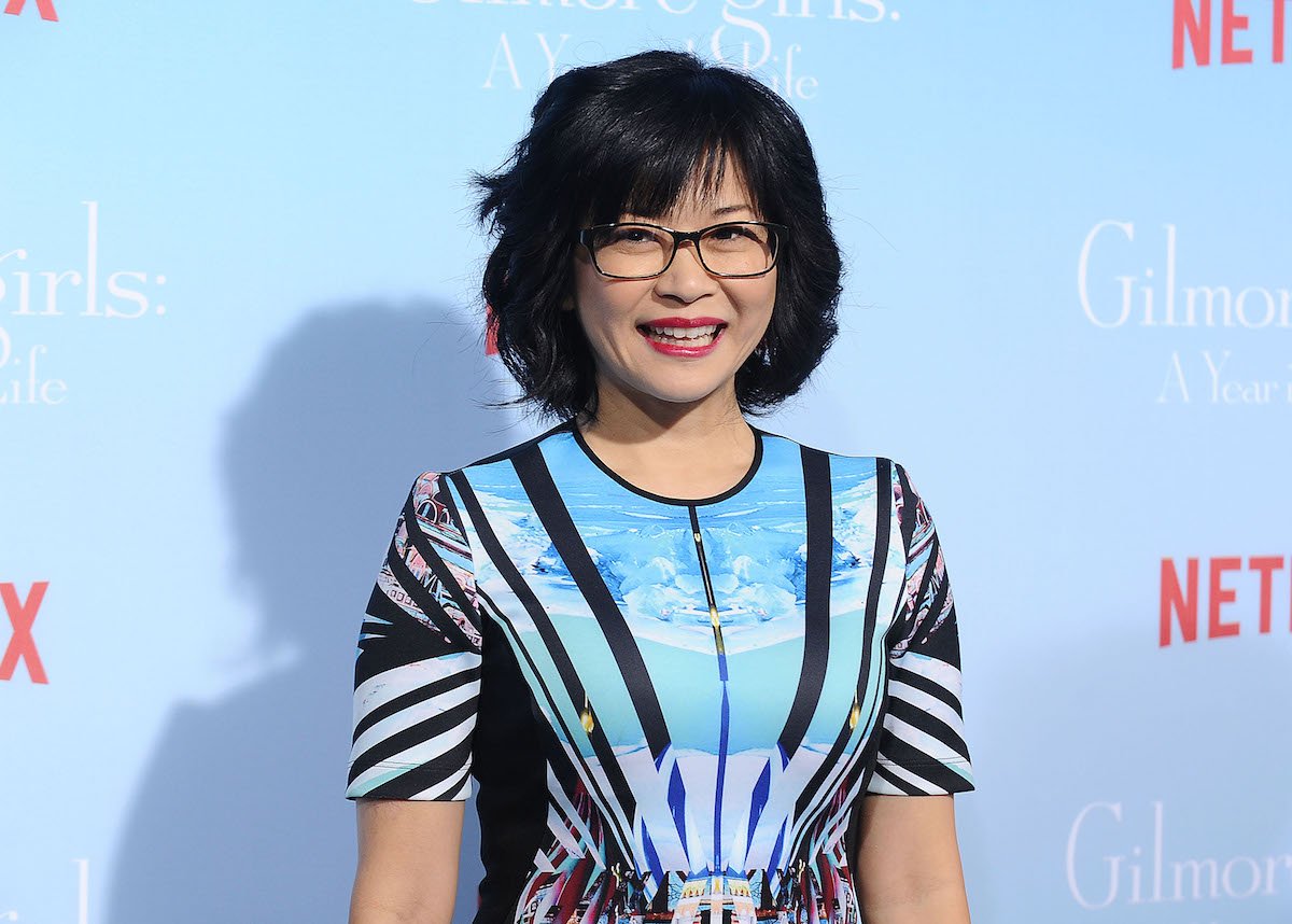 Acress Keiko Agena appears in front of a Gilmore Girls backdrop at an event.