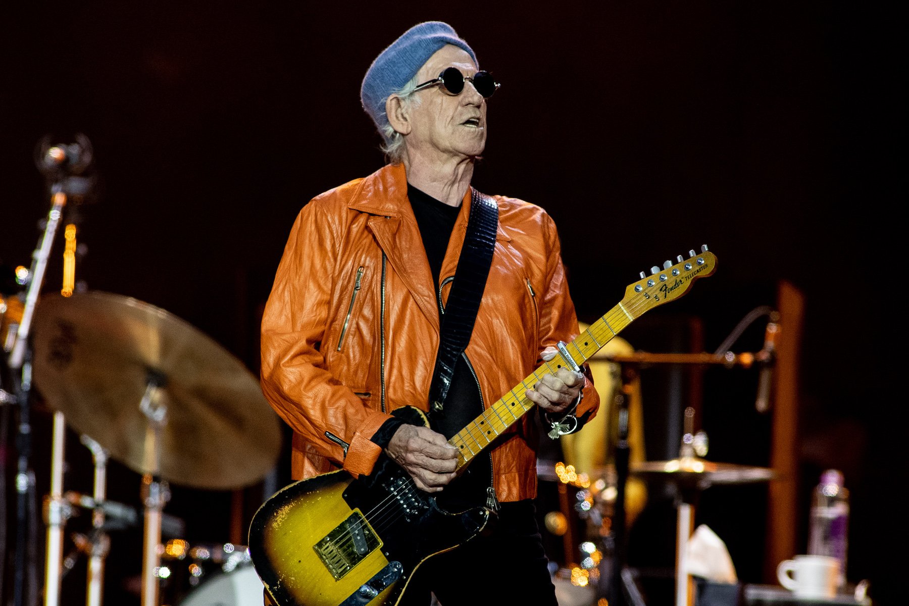 Keith Richards, who once helped Jimi Hendrix get his career off the ground, performing wearing an orange jacket in 2022