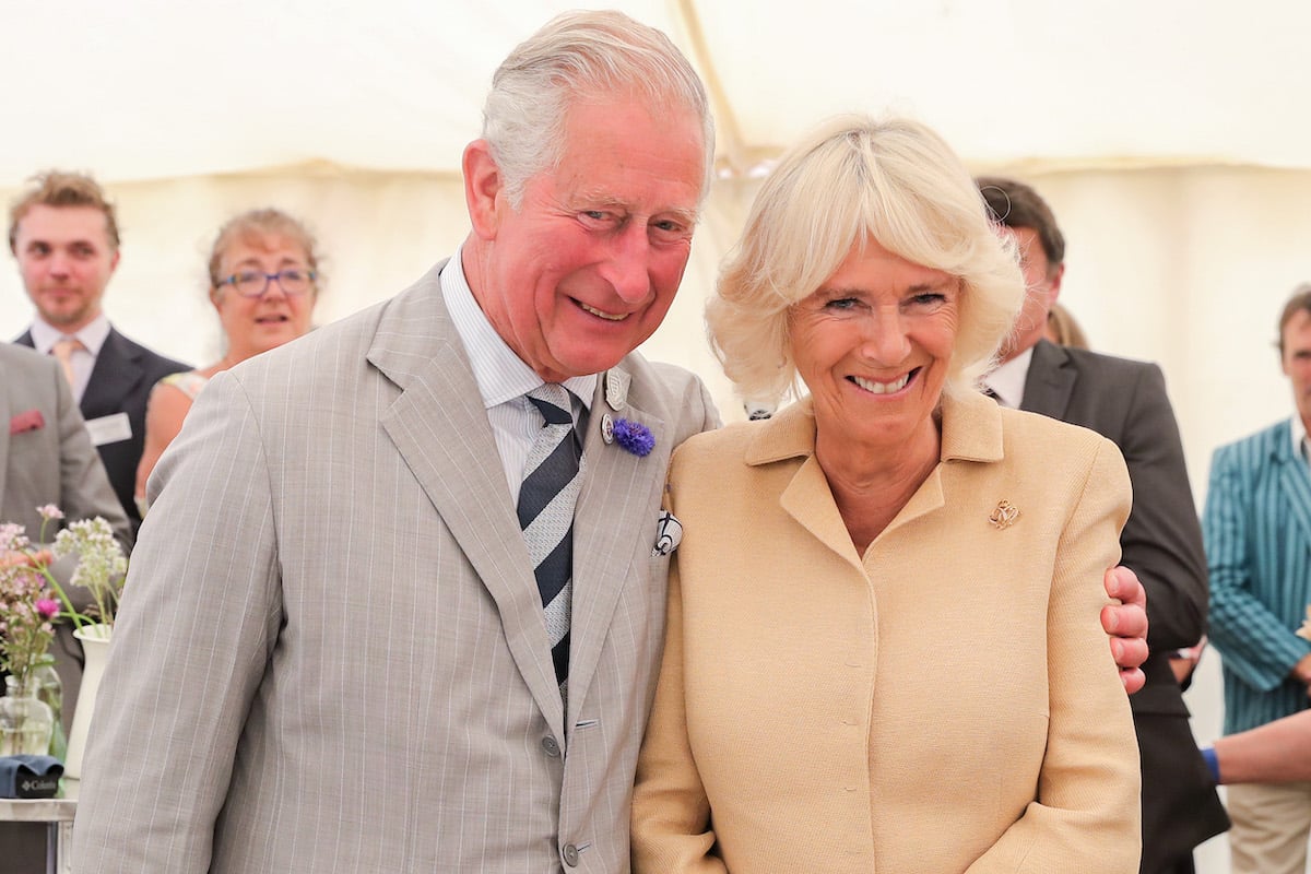 King Charles and Queen Consort Camilla smile and pose together at an event.
