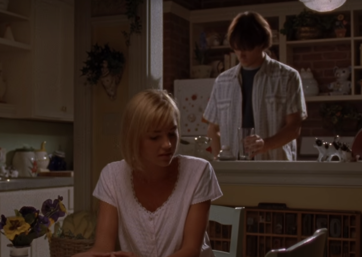 Dean Forrester stands at the counter of his apartment while his wife, Lindsay Lister, sists at the Kitchen table in an episode of 'Gilmore GIrls'