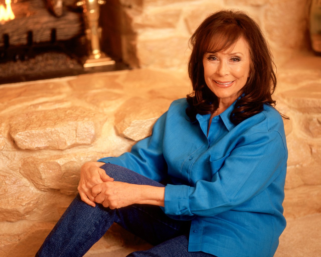 Loretta Lynn poses for a portrait in front of her fireplace circa 1997 in Hurricane Mills, Tennessee, a town she purchased.
