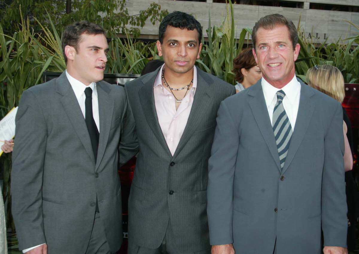Joaquin Phoenix, director M. Night Shyamalan and Mel Gibson pose for photos at the "Signs" premiere in 2002