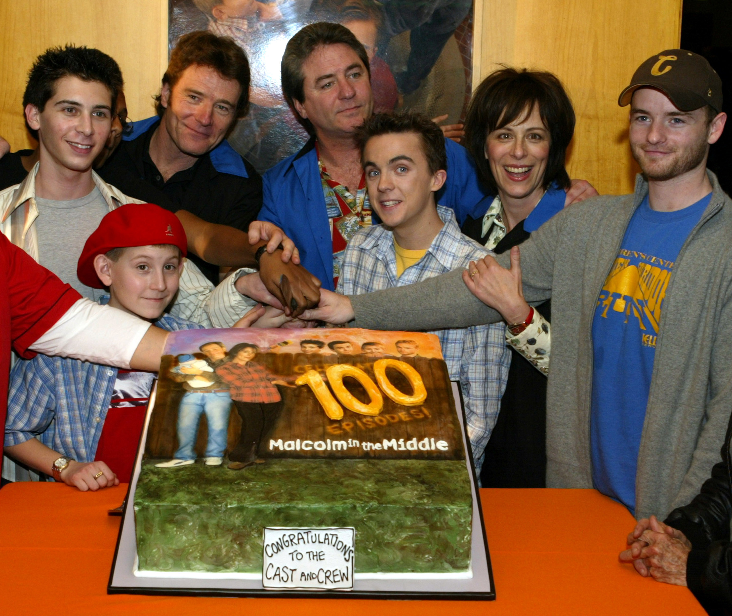 The cast of 'Malcolm in the Middle' pose with a cake celebrating the show's 100th episode