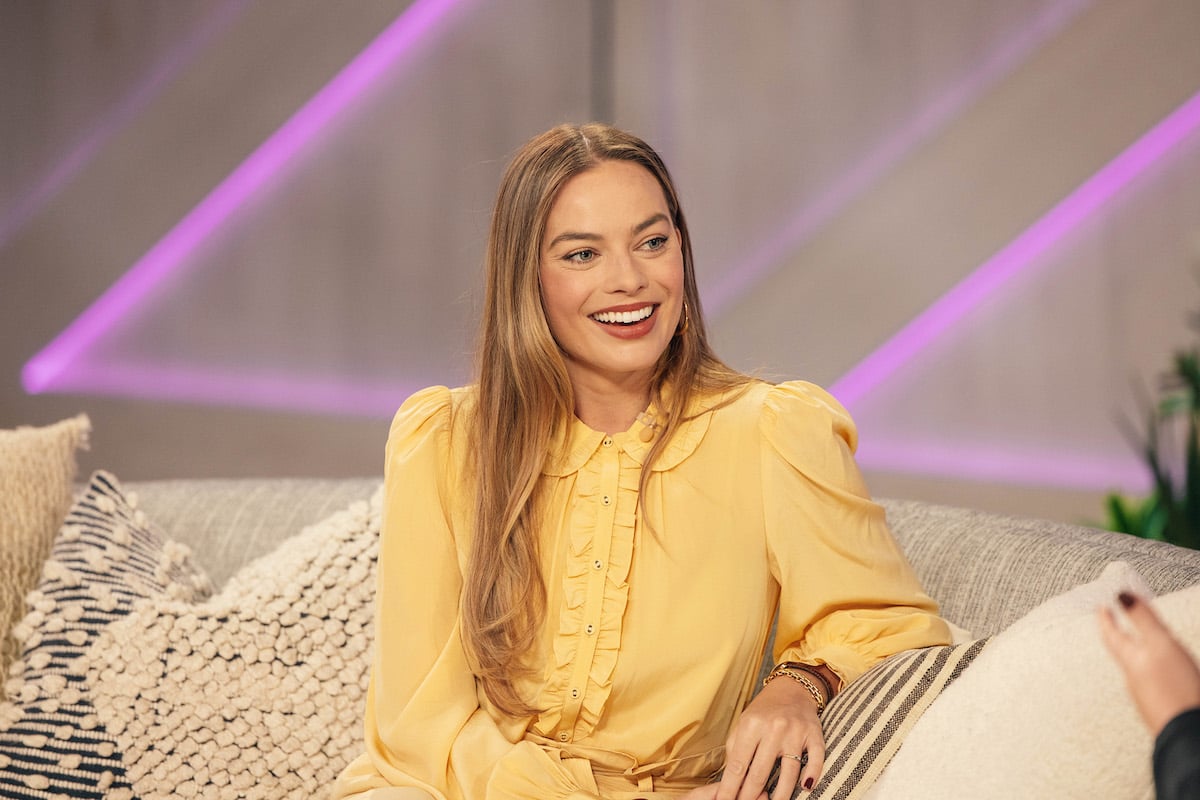 Margot Robbie star of The Wolf of Wall Street sits on the couch in a yellow gown