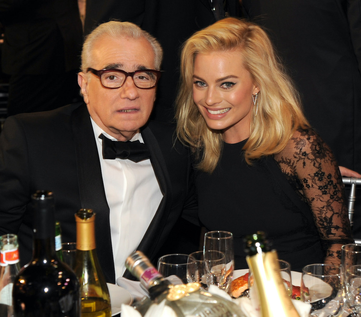 Martin Scorsese and Margot Robbie dressed in black at a dinner table