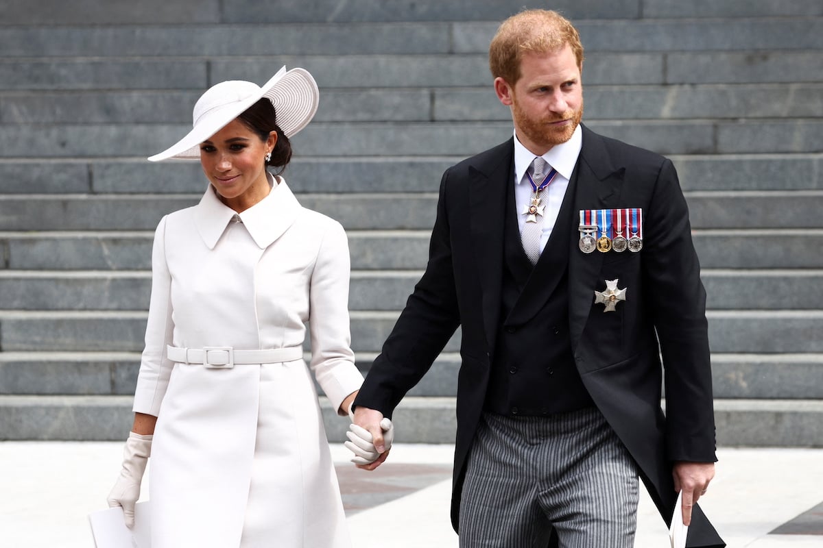 Meghan Markle and Prince Harry, whom the. royal family could be attempting reconciliation with ahead of the coronation, according to an expert, hold hands