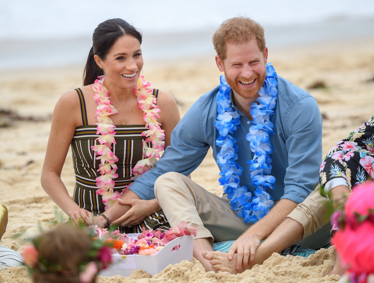 Meghan Markle, who Prince Harry said he warned during their 2018 royal tour in 'Spare', sits next to Prince Harry on a beach in Australia