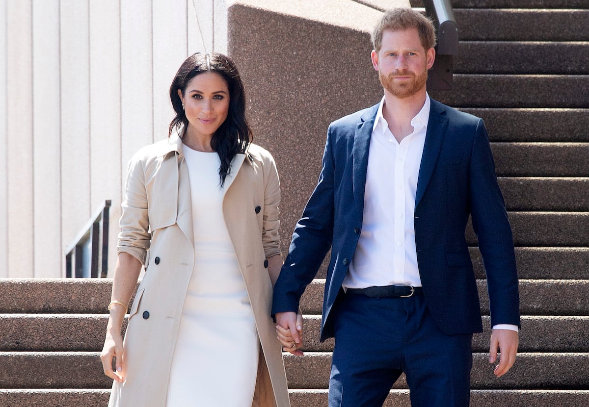 Meghan Markle and Prince Harry, who claims in 'Spare' he warned Meghan Markle about 'doing too well' on 2018 royal tour, walk hand in hand in Sydney, Australia