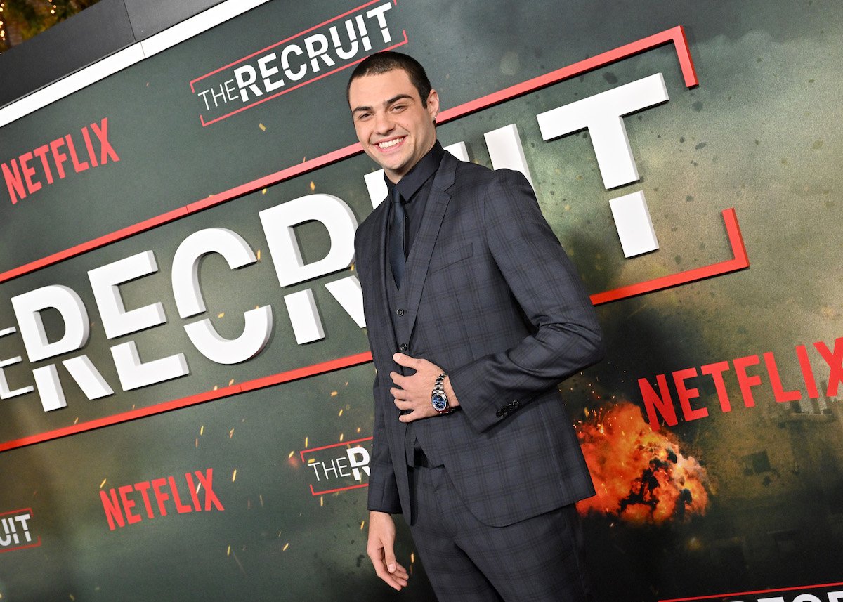 Noah Centineo poses on front of the logo for "The Recruit," a new show on Netflix.