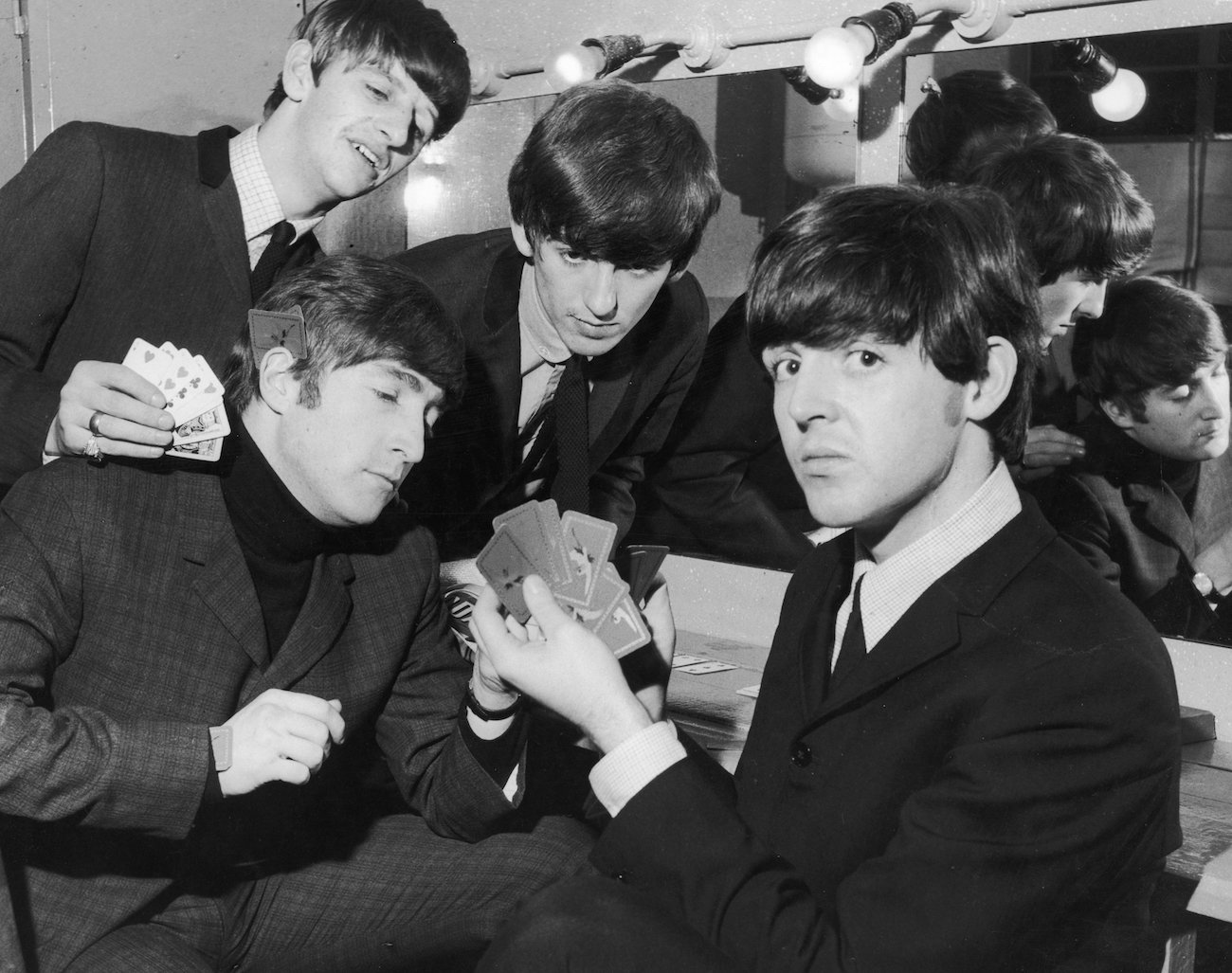 Paul McCartney and The Beatles playing cards in their dressing room in 1964.