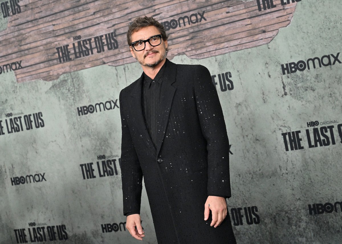 Pedro Pascal poses for cameras in front of a "The Last of Us" backdrop at a premiere event.