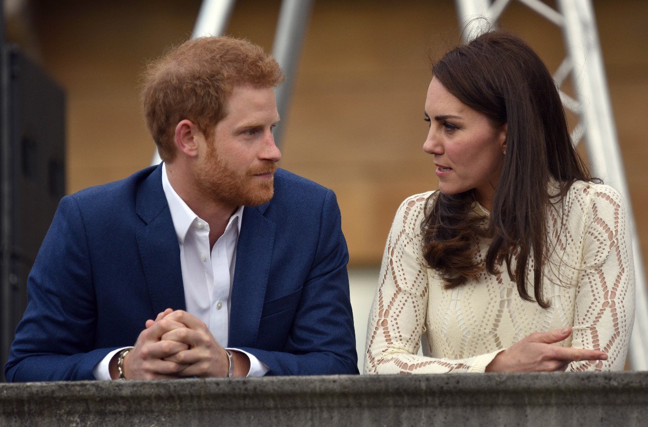 Prince Harry and Kate Middleton sit next to each other and talk.