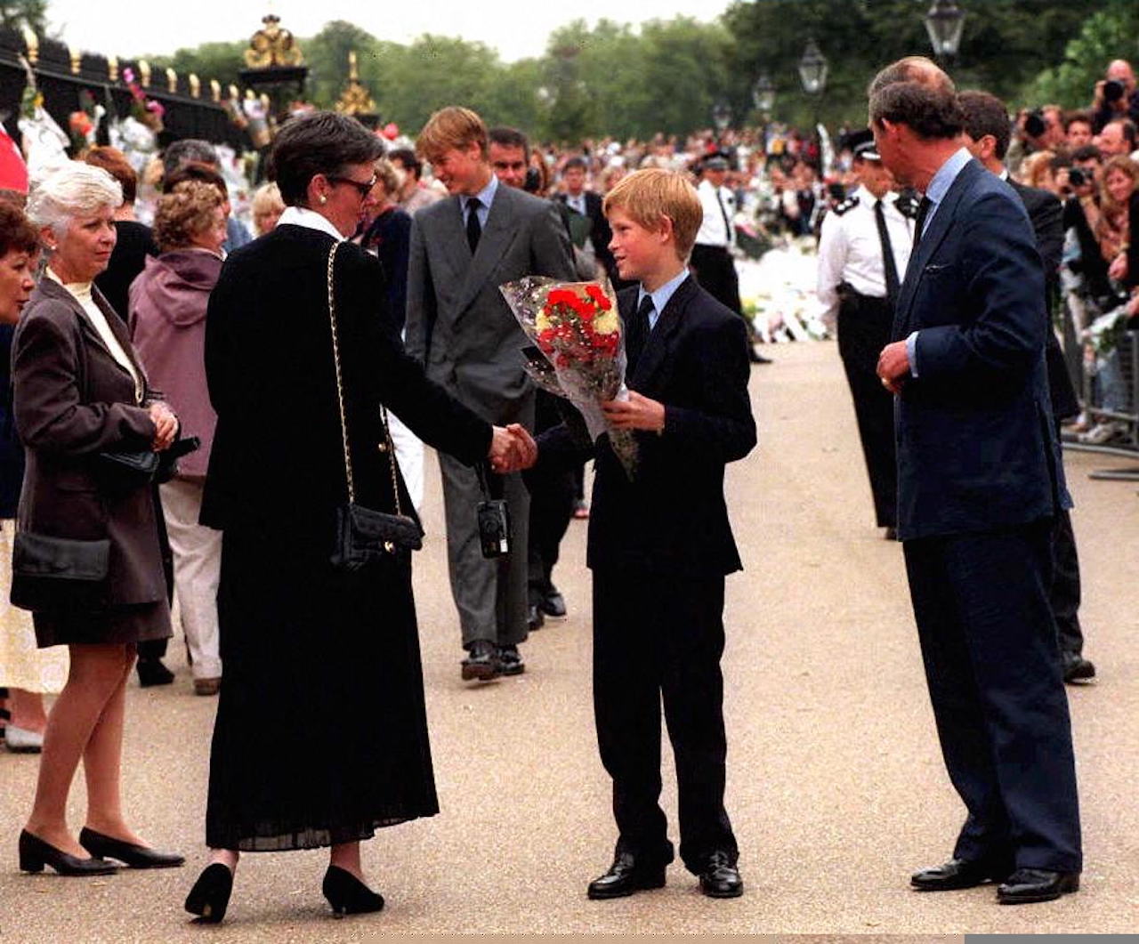 The future King Charles (R) and his sons Prince William (C background) and Prince Harry (C front) receive condolences and floral tributes for their mother, Diana, Princess of Wales, from mourners waiting outside Kensington Palace in London,