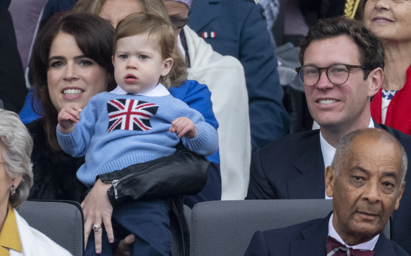 Princess Eugenie holding her son next to Jack Brooksbank at a crowded event