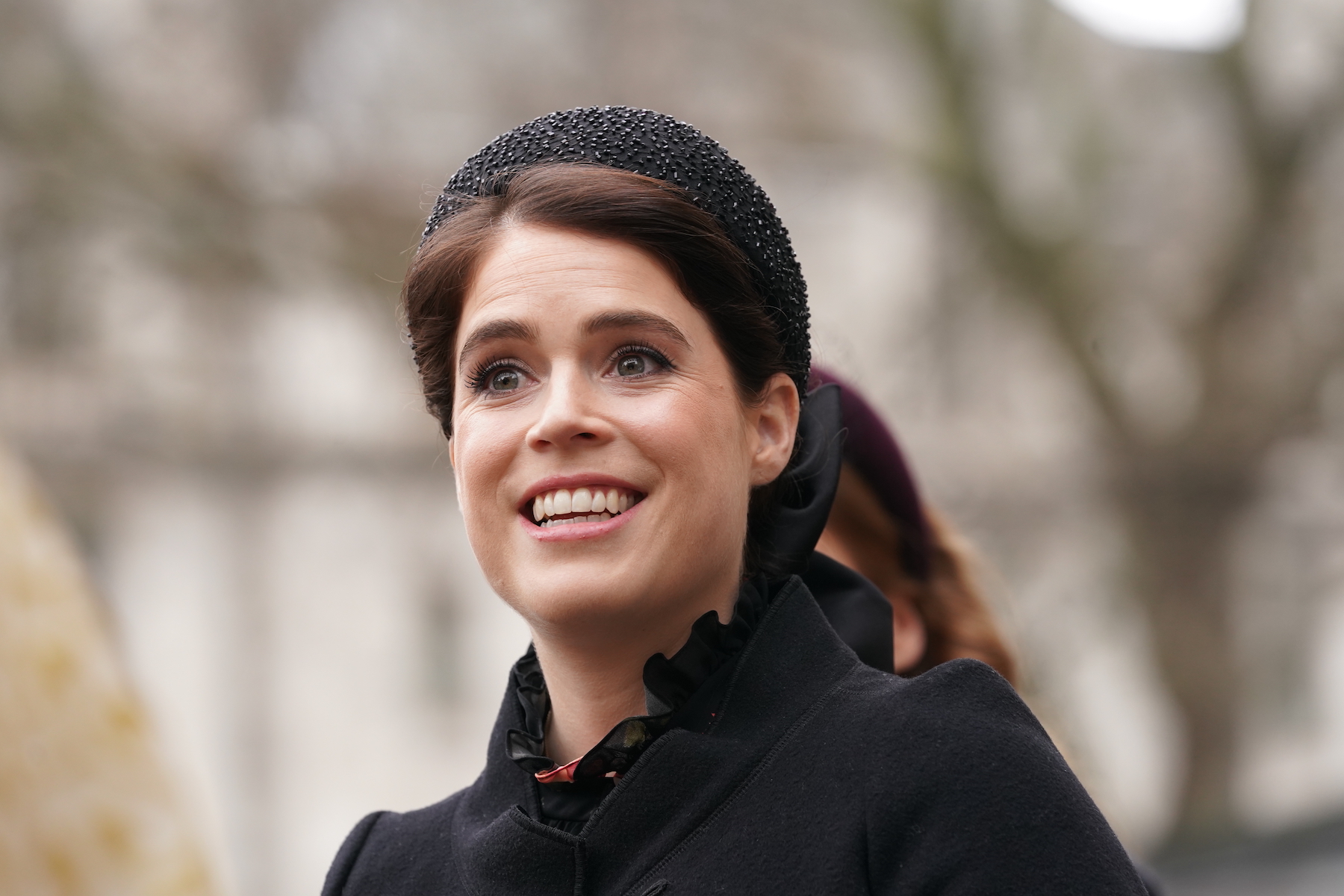 Princess Eugenie dressed in all black and smiling outdoors
