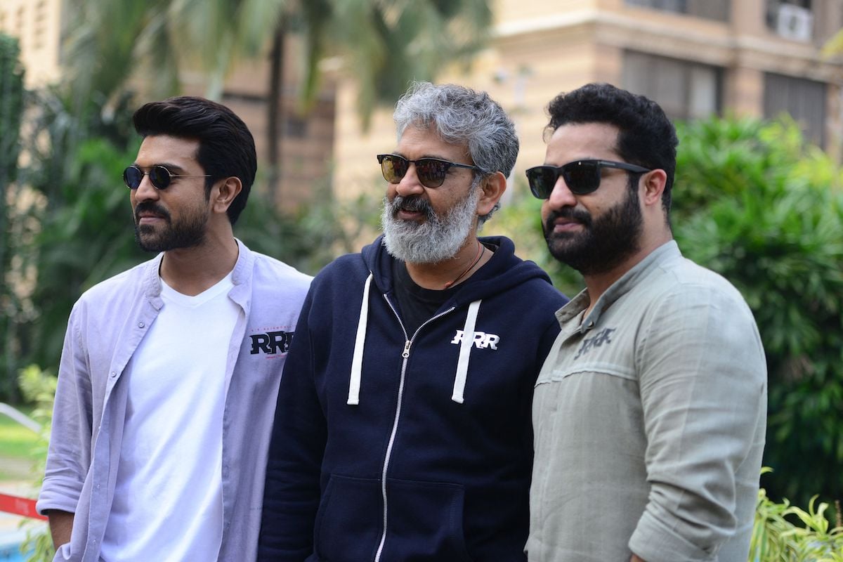 Actors Ram Charan and N.T. Rama Rao pose with S.S. Rajamouli in an outdoor setting.