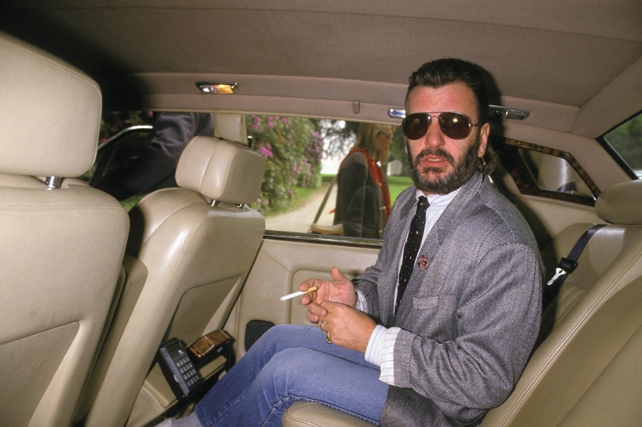 Beatles drummer Ringo Starr rides in the back of a car at a 1986 Fondation Cartier exhibition.