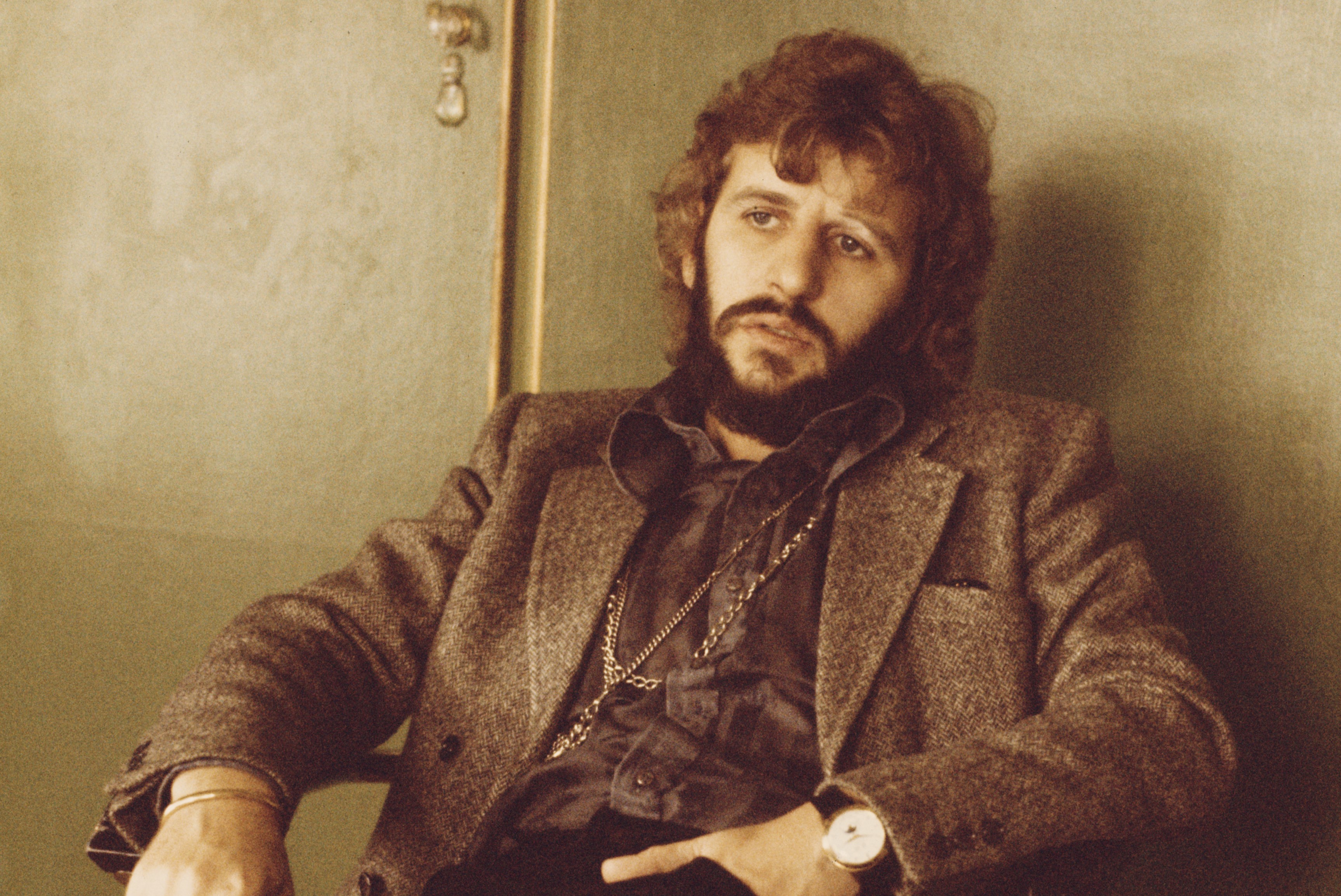 Ringo Starr sits with his hand in his pocket.