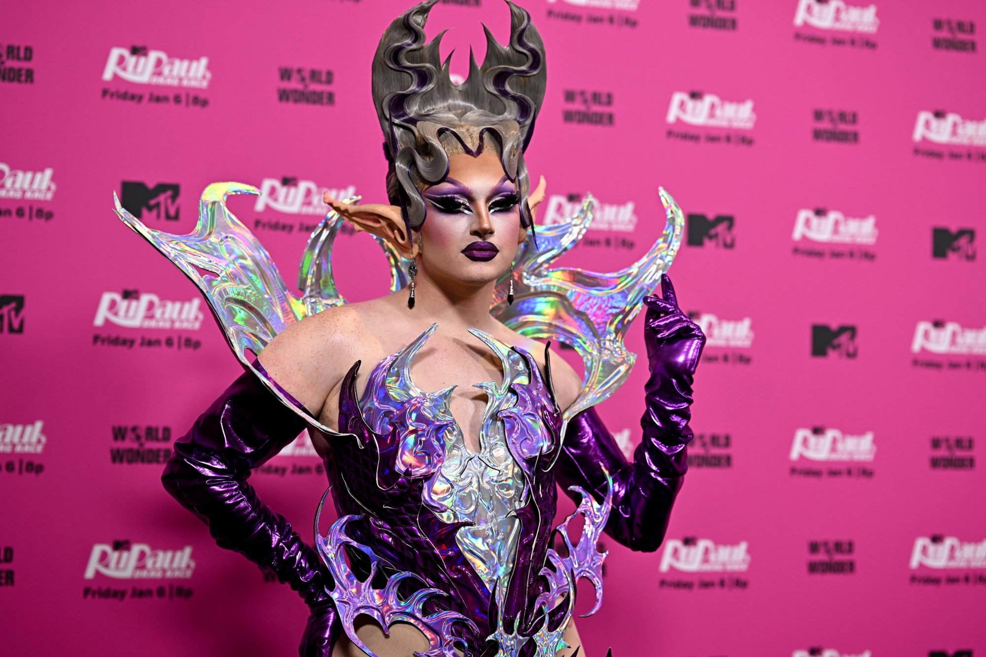 'RuPaul's Drag Race' Season 15 Irene Dubois wearing a purple costume standing in front of a pink step and repeat