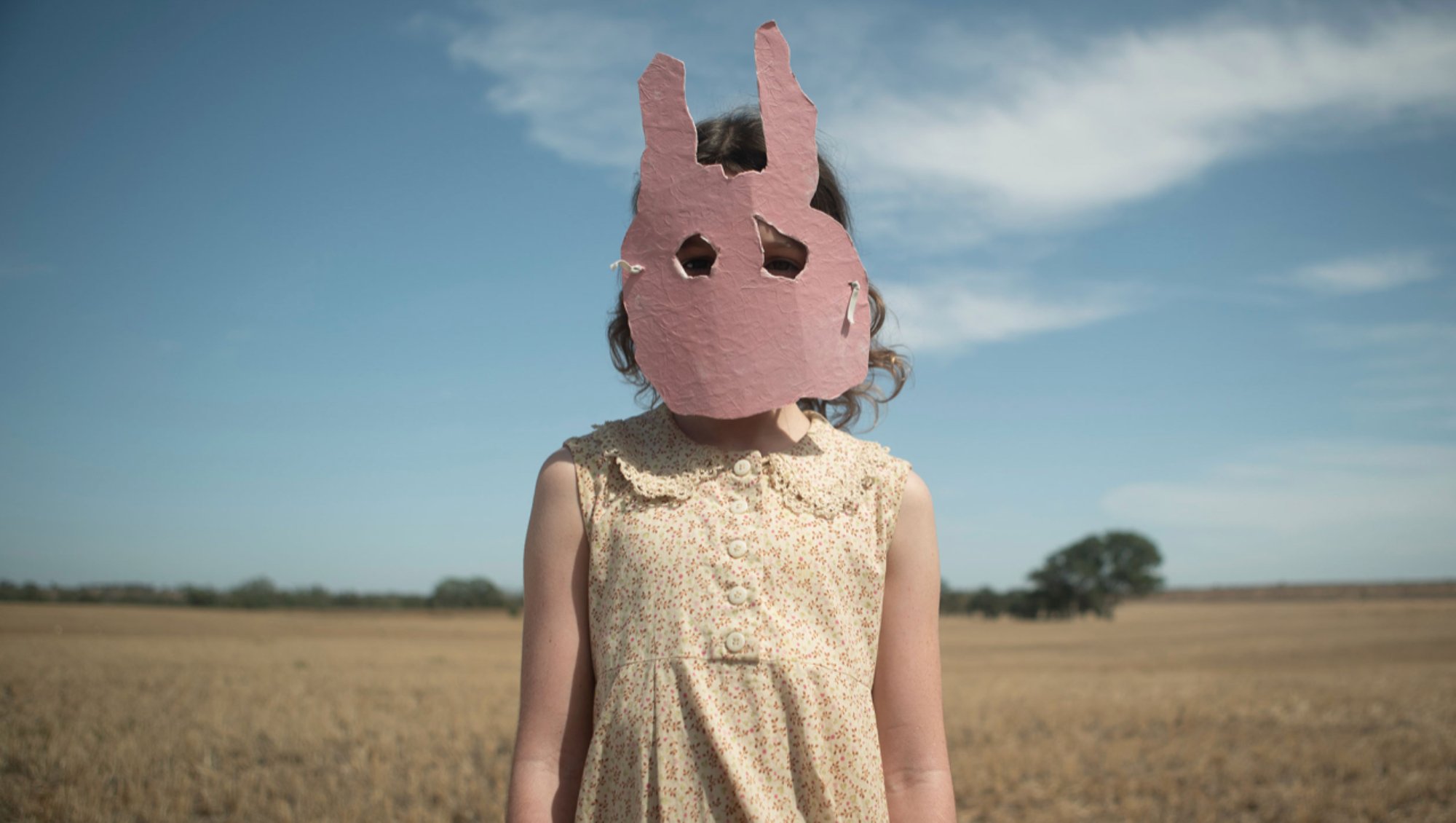 'Run Rabbit Run' Lily LaTorre as Mia wearing a bunny mask, standing in front of plains